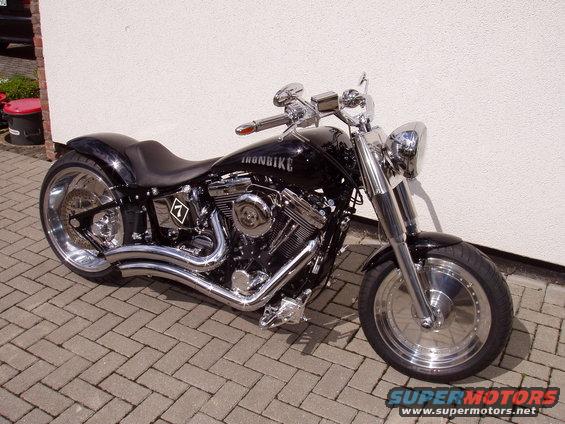 Black custom motorcycle with chrome accents parked on a brick patio. Text on the tank reads 'IRONBIKE'