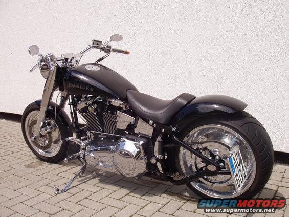 Black custom motorcycle with chrome accents and a wide rear tire, parked on a paved surface