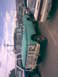 1995 Ford Bronco - A vintage green Ford F-100 truck is seen from the front-three-quarter angle, parked in a lot with other cars.
