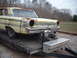 1963 Ford Galaxie - This weathered car, likely a 1963 model, is being transported on a trailer, missing its headlights and showing significant rust.