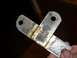 1980 Honda CB750 - A metal bracket with two holes is held by a hand. The bracket shows signs of wear and discoloration.
