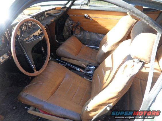 1969 Volvo P1800 interior with brown leather seats, wooden steering wheel, and wood-paneled doors