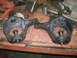 1995 Ford Bronco - Two black suspension knuckles with ball joints are laid out on a workbench, possibly for repair or replacement.