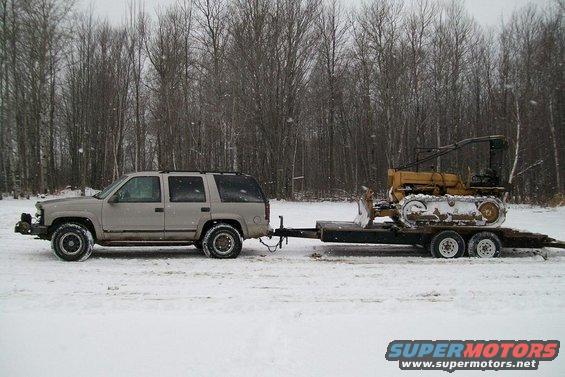 SUV towing a bulldozer on a trailer in the snow