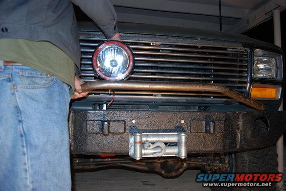 Front bumper with winch, grille, and spotlight being held by a person