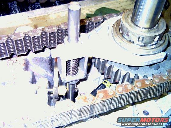 Close-up of a transfer case with a chain and gears. A metal arm with a spring is visible