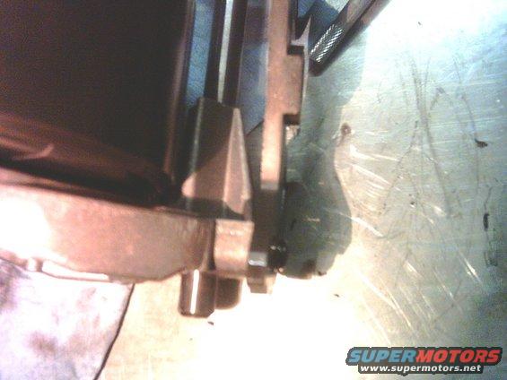 Close-up of a metal part, possibly a transfer case component, with visible bolts and a textured surface