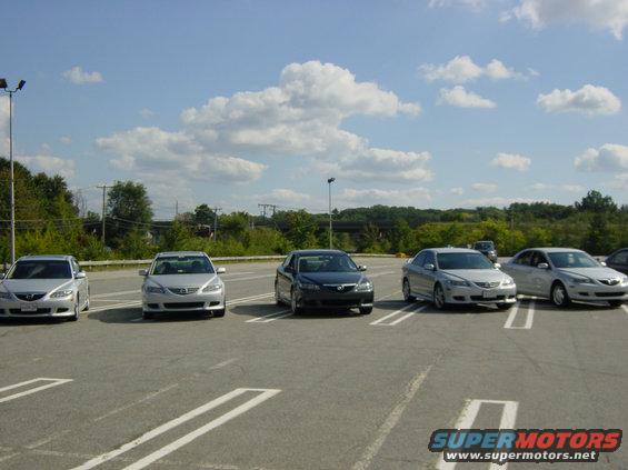 Five Mazda 6 sedans parked in a lot. One is dark gray, the others are silver. The one on the far right has a SuperMotors.net watermark