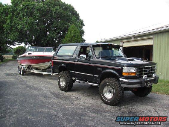 1995 Ford Bronco towing a red and white boat on a trailer