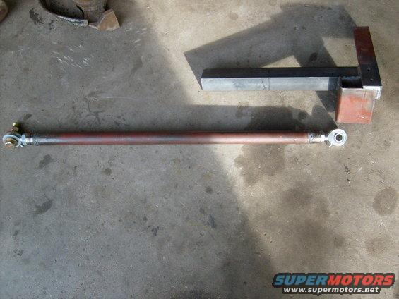 Custom metal rod with heim joints on each end, next to a metal bracket
