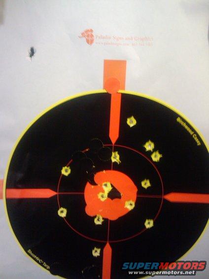 Target with multiple bullet holes, some in the center orange circle. Text reads 'Birchwood Casey' and 'Shoot-N-C Target'
