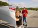 2003 Mazda 6 - A woman inspects the trunk of a silver 2003 Mazda 6, with a man standing in the background of a parking lot.