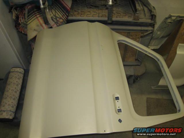 Unpainted vehicle door, possibly for a truck, in a workshop setting