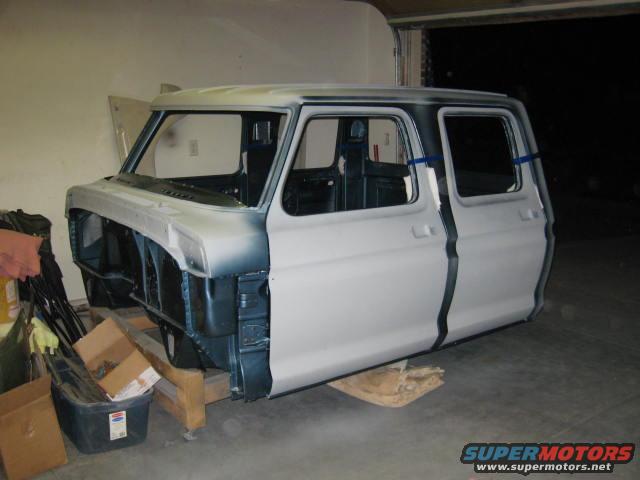 Ford truck cab, primer gray, on wooden stands, front end removed, side view
