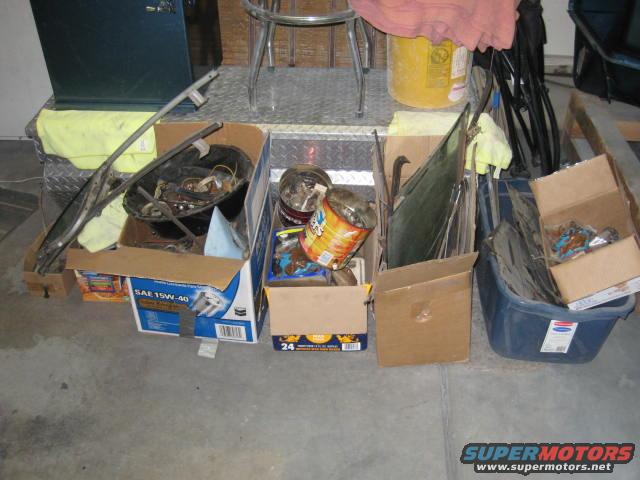 Boxes of car parts, including glass and trim, are stored in a garage