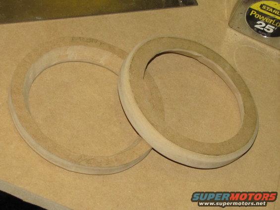 Two wooden speaker mounting rings on a workbench surface