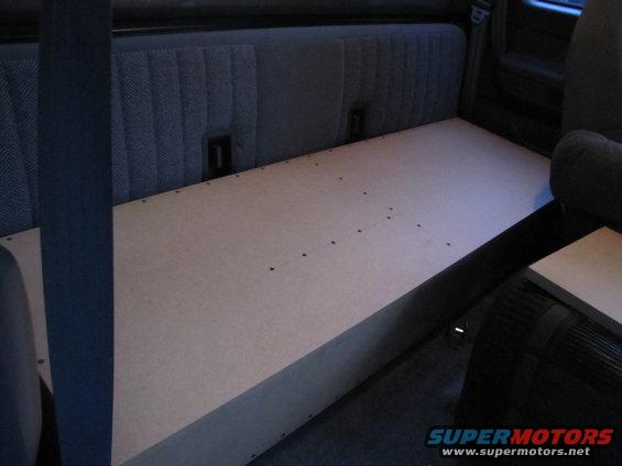 Interior shot of a truck cab with a custom wooden platform built over the rear seat area