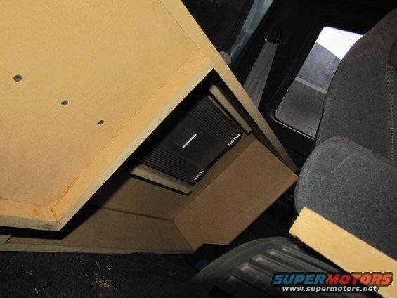 Custom subwoofer box with amplifier installed in vehicle interior, next to a seat