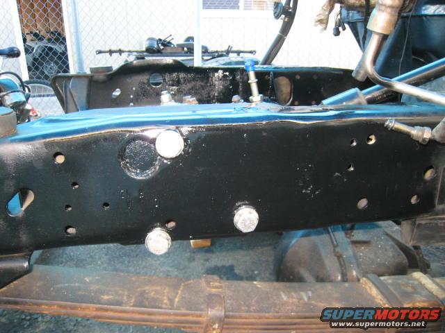 Close-up of a black truck frame with visible bolts and suspension parts