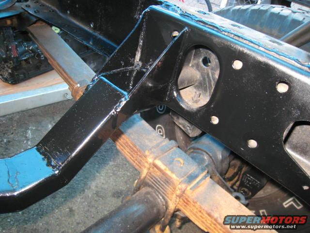 Close-up of a black painted truck frame with leaf springs and suspension components visible