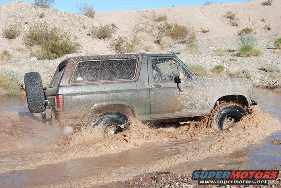 1982 Ford Bronco driving through mud, side view