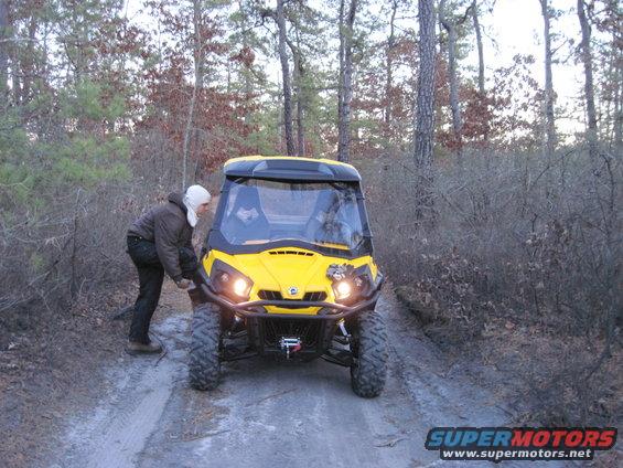 Yellow Can-Am ATV on a dirt path with a person pushing it