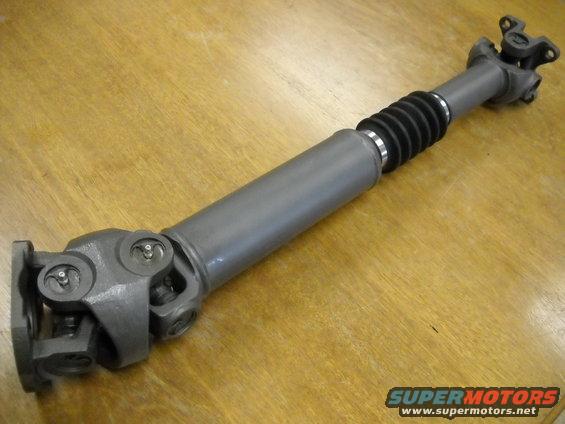 Gray driveshaft with black bellows and U-joints on a wooden surface