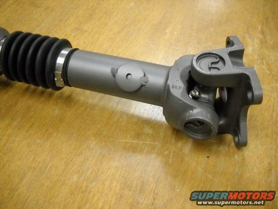 Gray driveshaft with a black rubber boot and a U-joint assembly. There's a small circular cap on the shaft