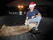 2006 Dodge 2500 - A man in a Santa hat poses with a deer in the back of a blue pickup truck.