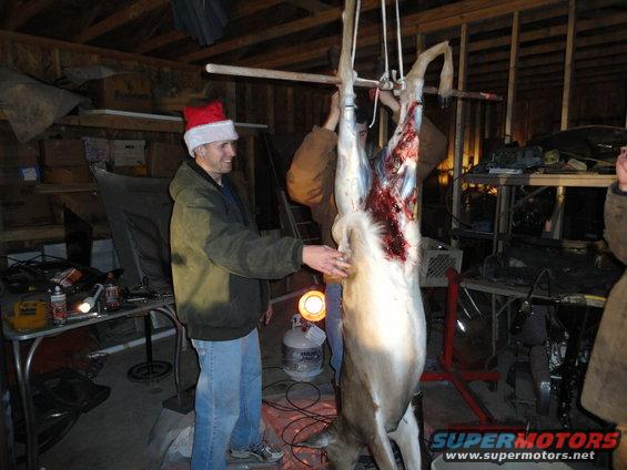 guy in santa hat next to hanging deer in garage