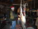 2006 Dodge 2500 - A man in a Santa hat stands by a deer carcass being prepped in a garage.