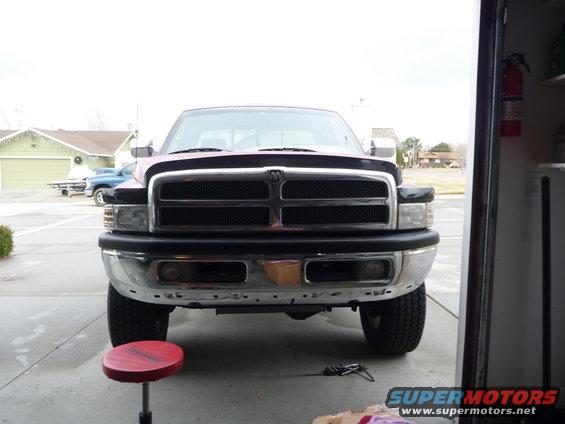 Front view of a dark red Dodge Ram pickup truck, parked in a driveway, with a red mechanic's stool in the foreground