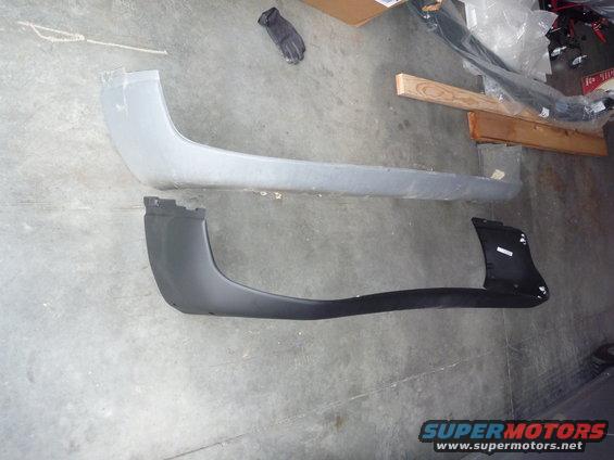 Two bumper covers, one gray and one black, laid out on a concrete floor