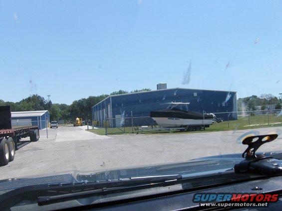 Boat on a trailer parked in front of a blue industrial building