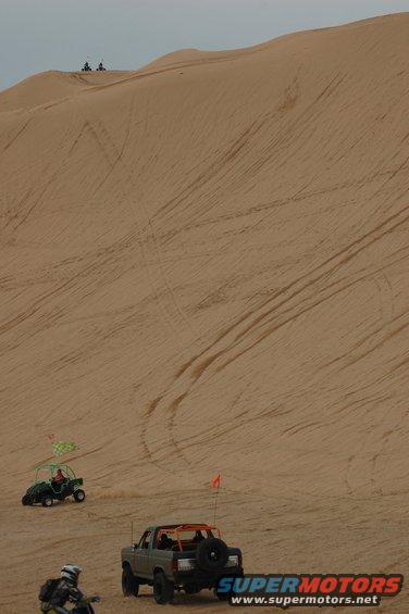 Gray 1982 Ford Bronco with spare tire on rear, on sand dune