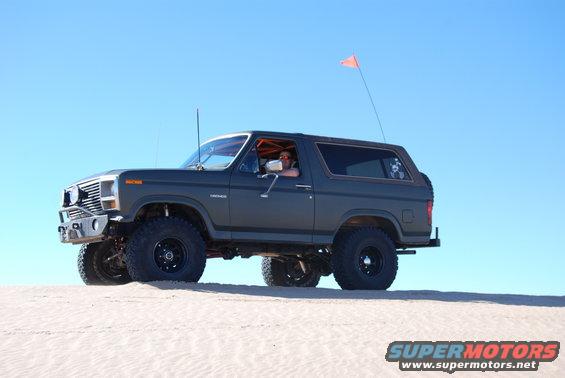 Dark gray 1980 Ford Bronco with off-road tires on sand dunes