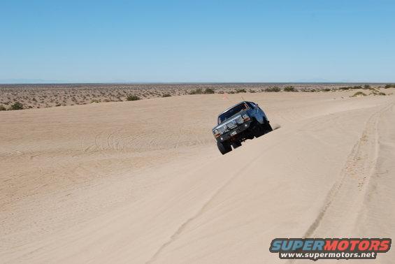 Ford Bronco climbing a sand dune in the desert