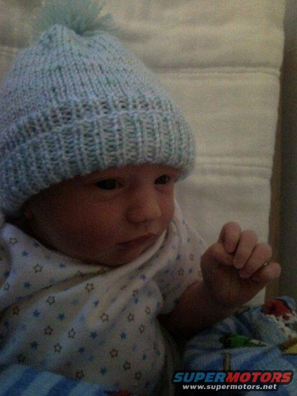 Baby wearing a light blue knitted hat with a pom-pom