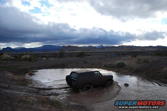 Dark brown SUV navigating a muddy water obstacle off-road