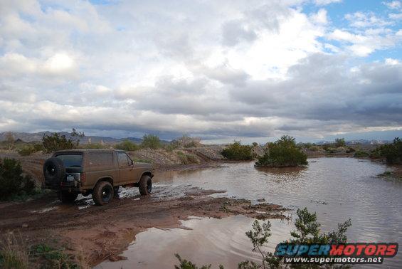 Brown 1982 Ford Bronco driving through muddy water