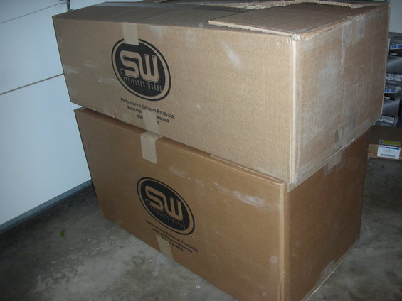 Two stacked cardboard boxes with "SW Stainless Works" logo and text "Performance Exhaust Products"