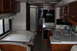 2003 Ford F-350 - The interior of a motorhome shows a dinette area, a kitchen with a sink and microwave, and a door leading to the bathroom.