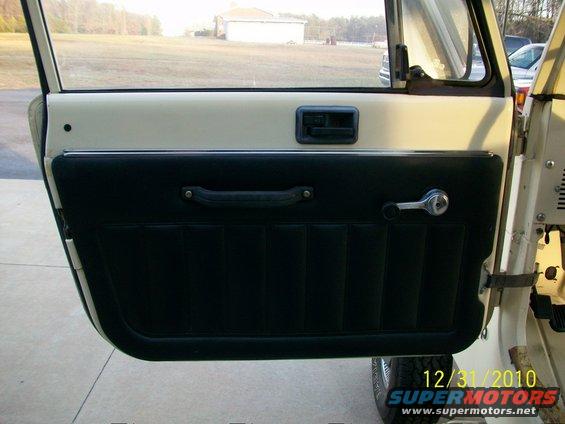 Cream and black interior door panel with chrome window crank and black handle