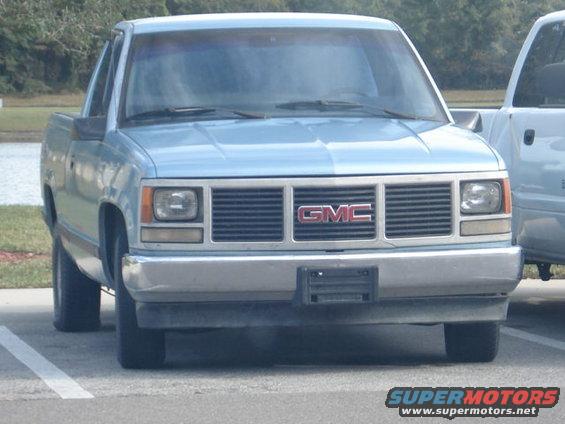 Light blue pickup truck with a chrome grille and GMC badging, parked in a lot
