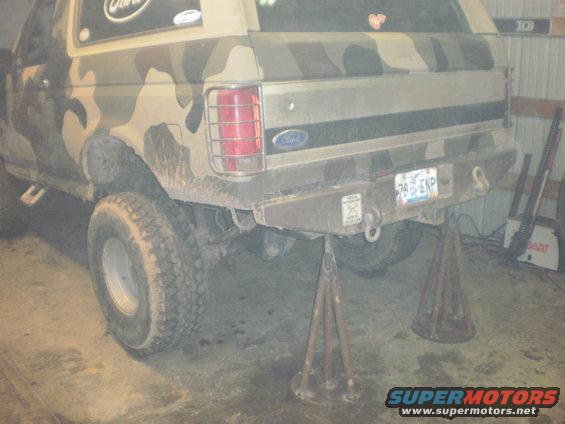 Rear of a camo-painted Ford Bronco on jack stands. License plate reads 786 ENP