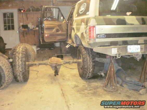 1992 Ford Bronco with rear axle removed, person working underneath