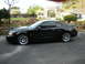 2003 Ford Mustang - A black 2003 Ford Mustang Cobra coupe is parked in a driveway with a backyard visible.