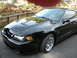 2003 Ford Mustang - This black 2003 Ford Mustang Cobra features distinctive hood scoops and chrome wheels, presented in a three-quarter front view.