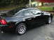 2003 Ford Mustang - Side view of a black 2003 Ford Mustang coupe showing its body lines and chrome wheels.