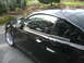 2003 Ford Mustang - A black coupe with shiny chrome wheels is parked outdoors on a paved surface.